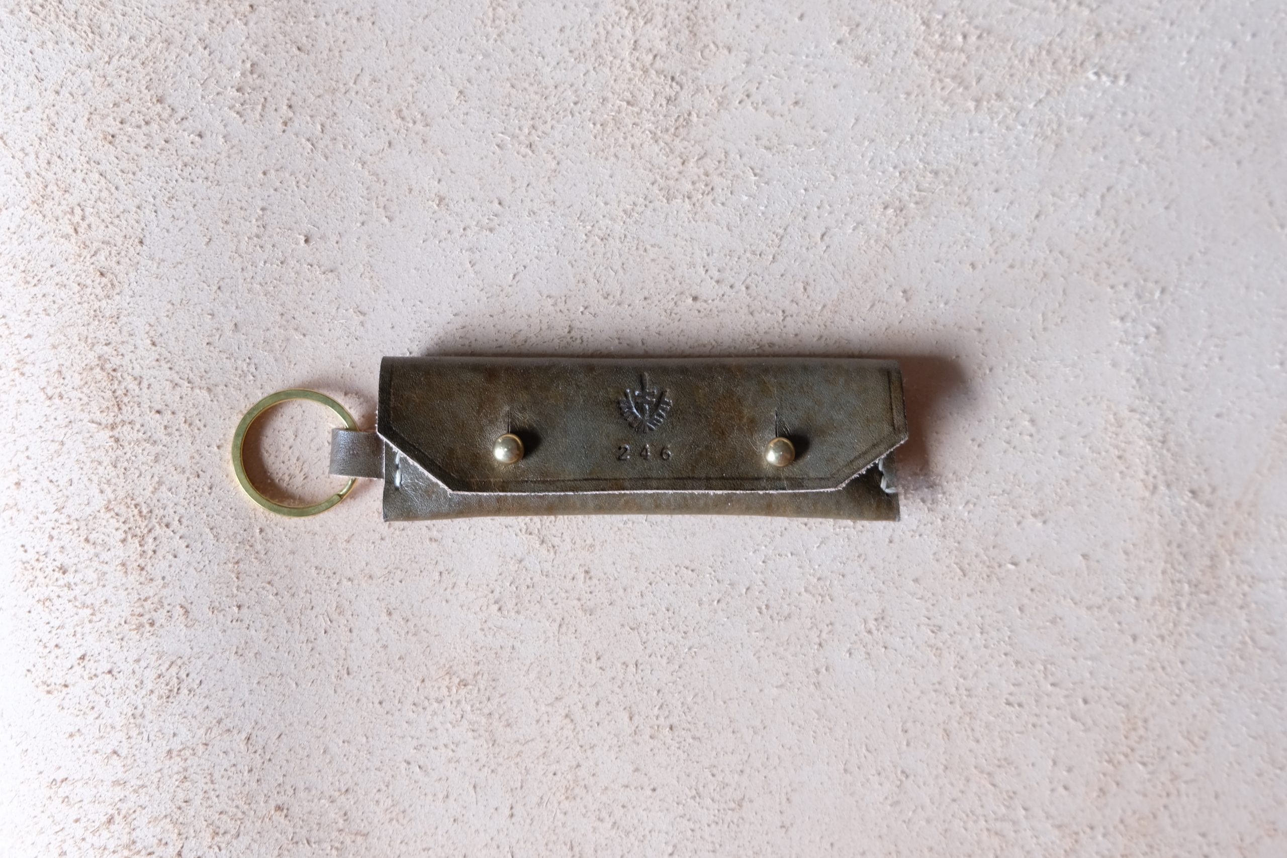lerif designs leather gum stick coin holder on beige background vinegaroon with brass ring