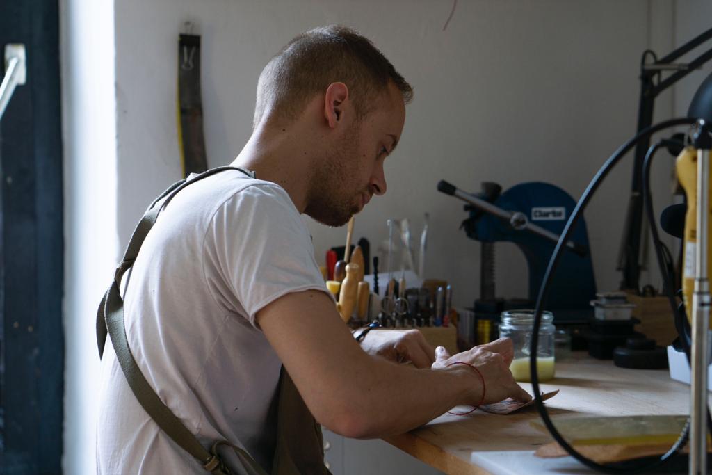 lerif designs leather craftsman at work bench finishing an item